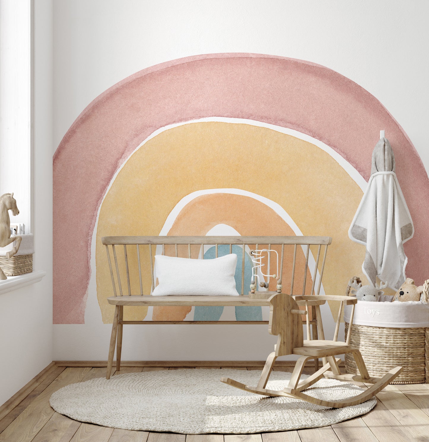 Watercolor Rainbow Colorful wallpaper mural in dusty pink and peach behind a wood spindle bench and rocking horse