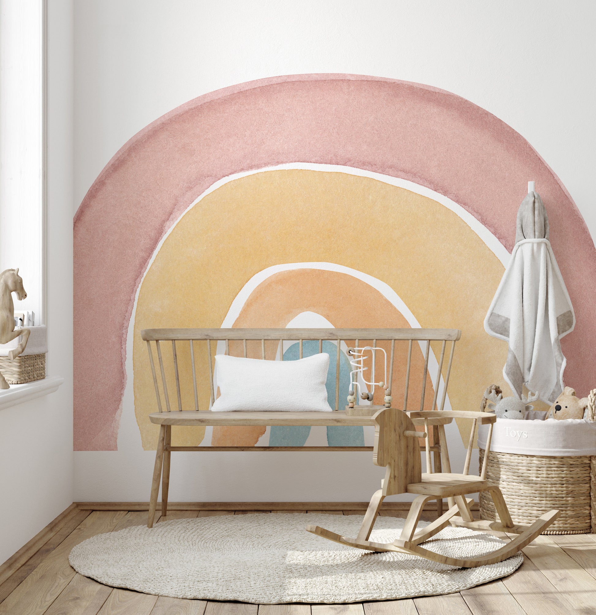 Watercolor Rainbow Colorful wallpaper mural in dusty pink and peach behind a wood spindle bench and rocking horse