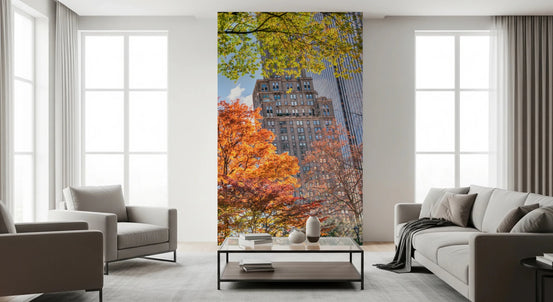 Colours of Central Park mural of autumn trees and city towers as a panel between a beige sofa and armchair