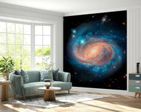 Cosmic Symphony wallpaper mural showing a spiral galaxy on the feature wall behind a sage green sofa in a living room