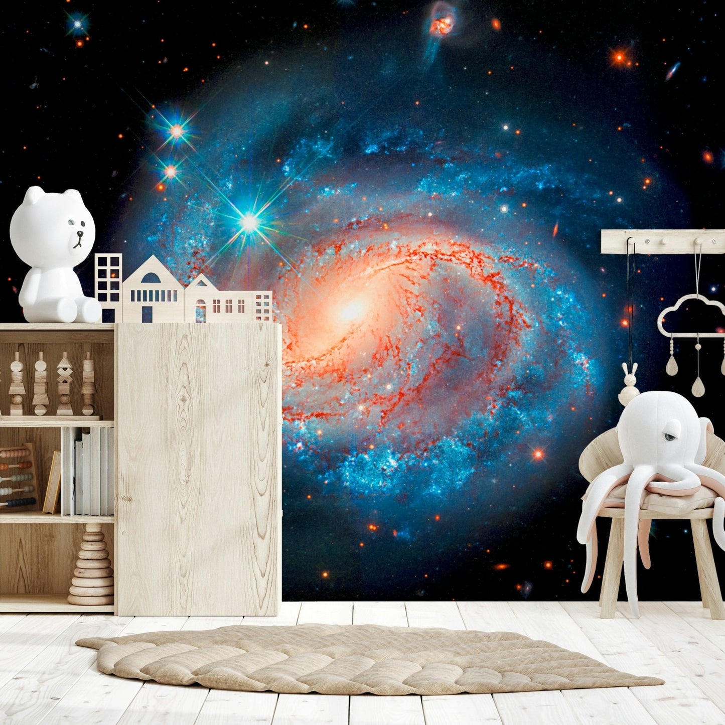 Cosmic Symphony wallpaper mural of a deep-space galaxy in a kids room with a bear lamp and octopus plush toy