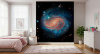 Cosmic Symphony wallpaper mural with a blue and orange galaxy behind a pink bed in a girls bedroom with star rug