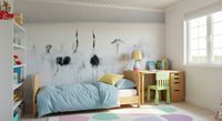 Crane Dance in White wallpaper mural of grey cranes behind a wood bed and green chair in a kids bedroom