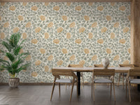 Dancing Bloom wallpaper with cream and ochre flowers behind a wood dining table and potted palm in a dining room