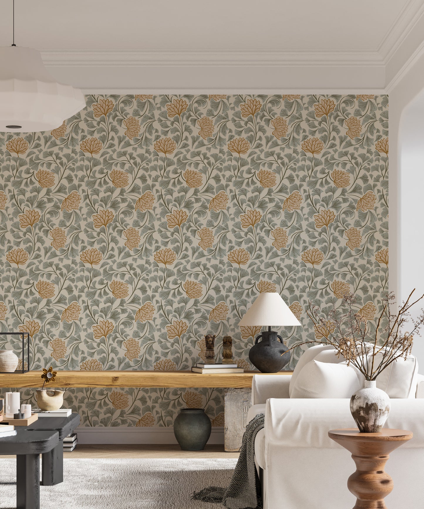 Dancing Bloom wallpaper with amber blooms and sage leaves behind a wood bench, white sofa and table lamp in a living room