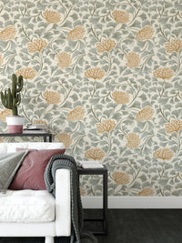Dancing Bloom wallpaper with orange flowers and grey ginkgo leaves behind a white sofa with pink cushions in a living room