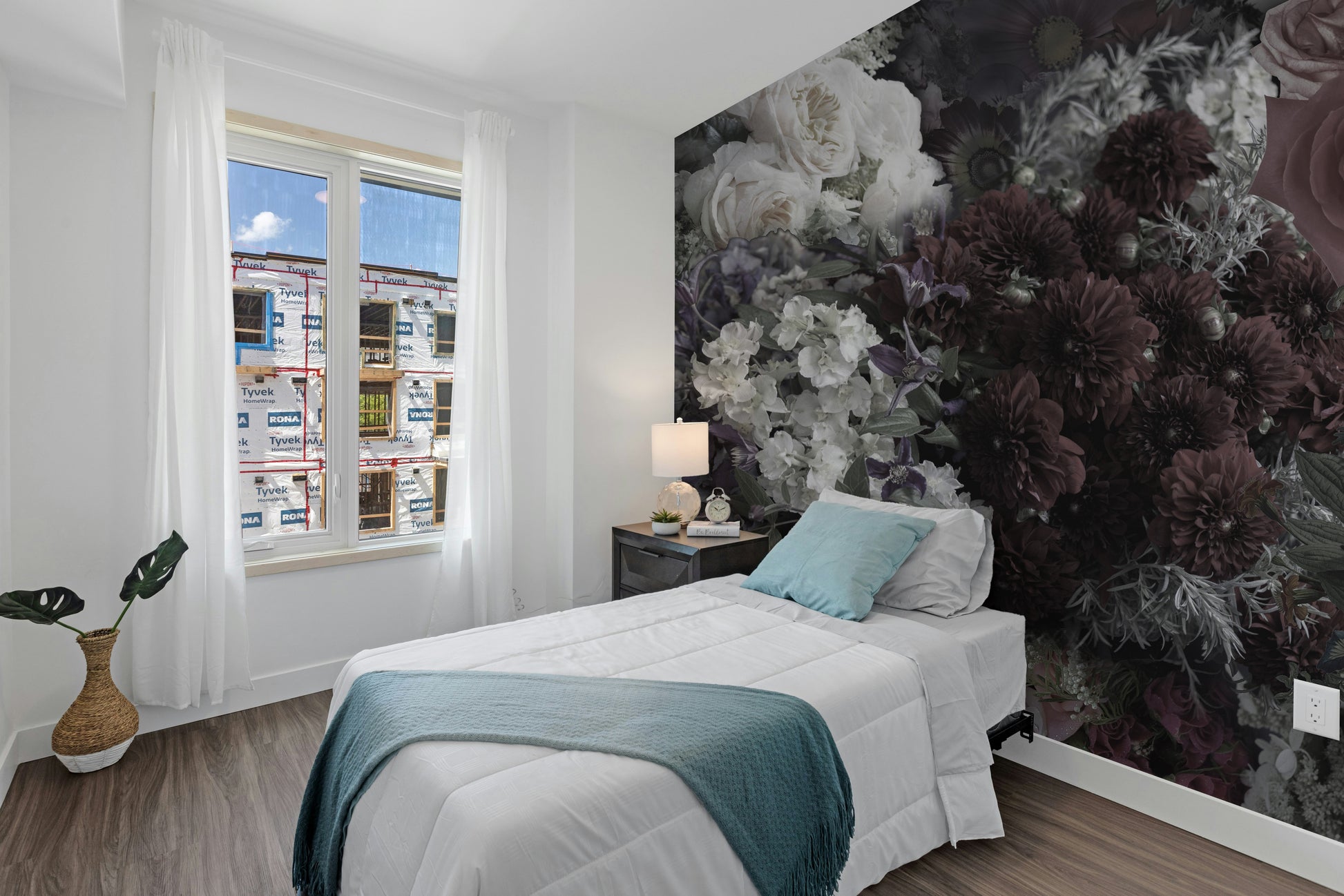 Dark Floral wallpaper mural as an accent wall behind a white bed with a teal throw in a bright bedroom