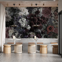 Dark Floral wallpaper mural behind pedestal tables and rattan stools in a moody dining seating area