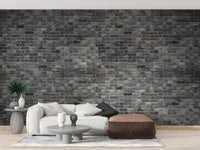 Dark Grey Brick Textured wallpaper mural styled as a feature wall behind a dining table and chairs in black tones