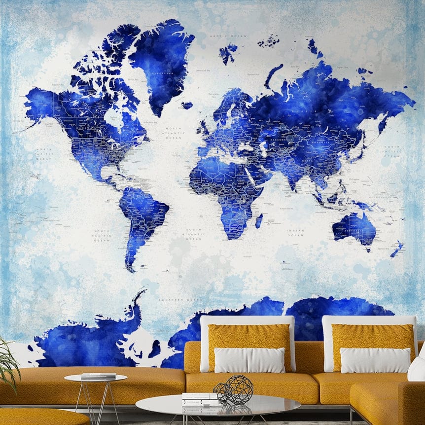 Deep Blue Watercolor World Map wallpaper above a mustard yellow sofa with white pillows and a glass table