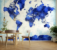 Deep Blue Watercolor World Map wallpaper behind a wood dining table and chairs with hanging bulb lights
