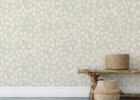 Dewy Birch Branches wallpaper in sage green behind a rustic wood bench with woven baskets