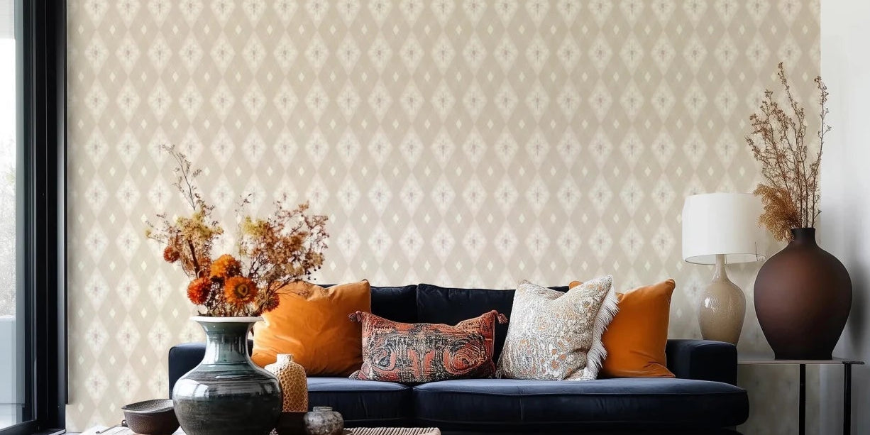 Diamond Bloom wallpaper in beige with a cream floral diamond pattern behind a navy velvet sofa with orange pillows in a living room