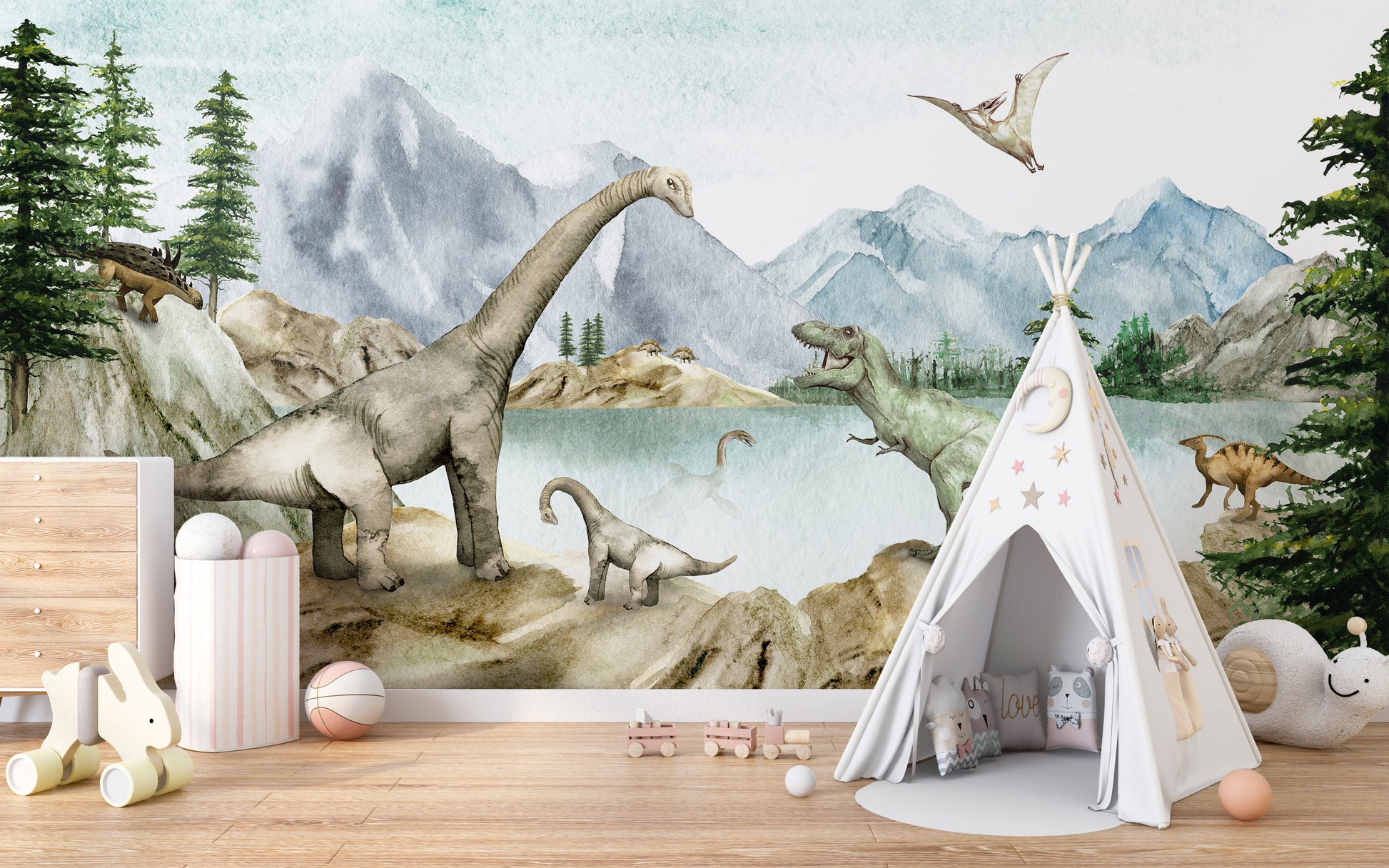 Dino dreams wallpaper mural of dinosaurs and blue mountains behind a white play teepee and toys in a kids room