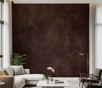 Dirty Paper Cognac wall mural in deep brown behind a cream sectional, leather chairs and an orchid in a tall living room