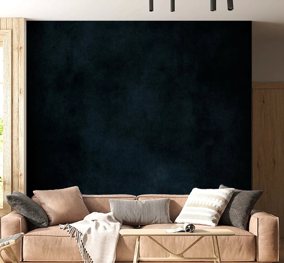 Dirty Paper Midnight wall mural in dark navy plaster behind a tan leather sofa with knit throw in a living room