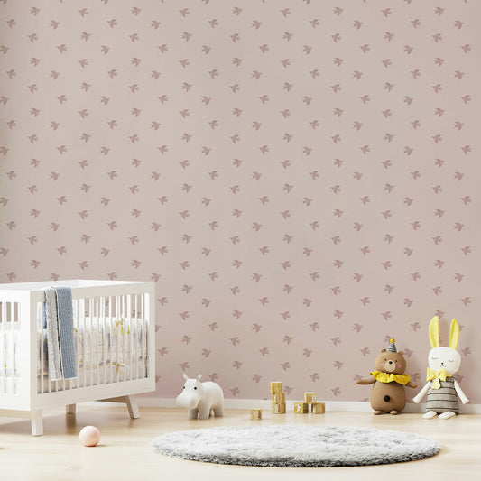 Dreamy Birds Shell Pink wallpaper with dusty pink birds behind a white crib, teddy bear and bunny toys in a cozy nursery