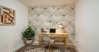 Dusty White Botanical Bloom Waves wallpaper in a home office behind a light wood desk, cream chair and fiddle-leaf fig