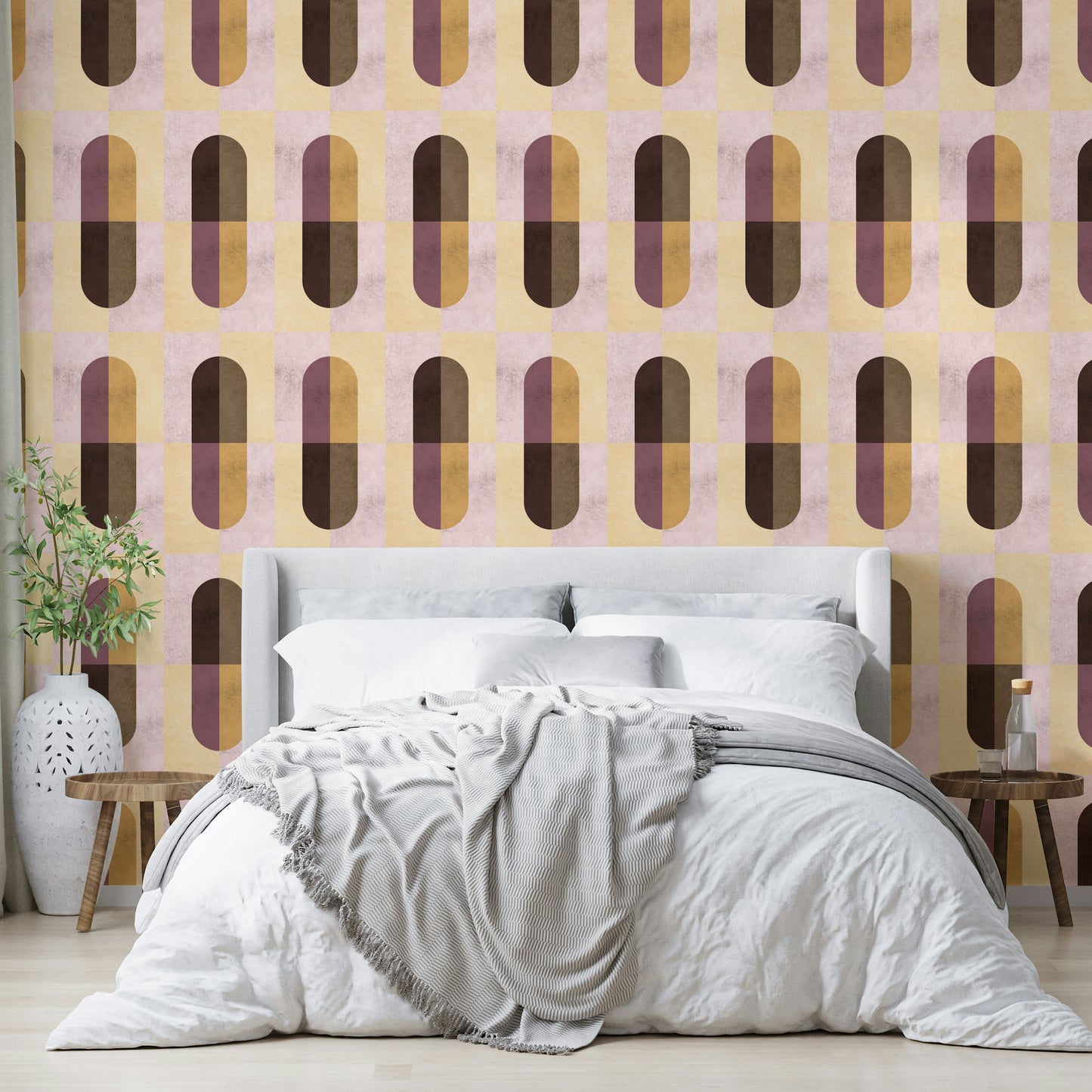 Earthy Geometric wallpaper behind a white upholstered bed with a grey throw and an olive branch vase