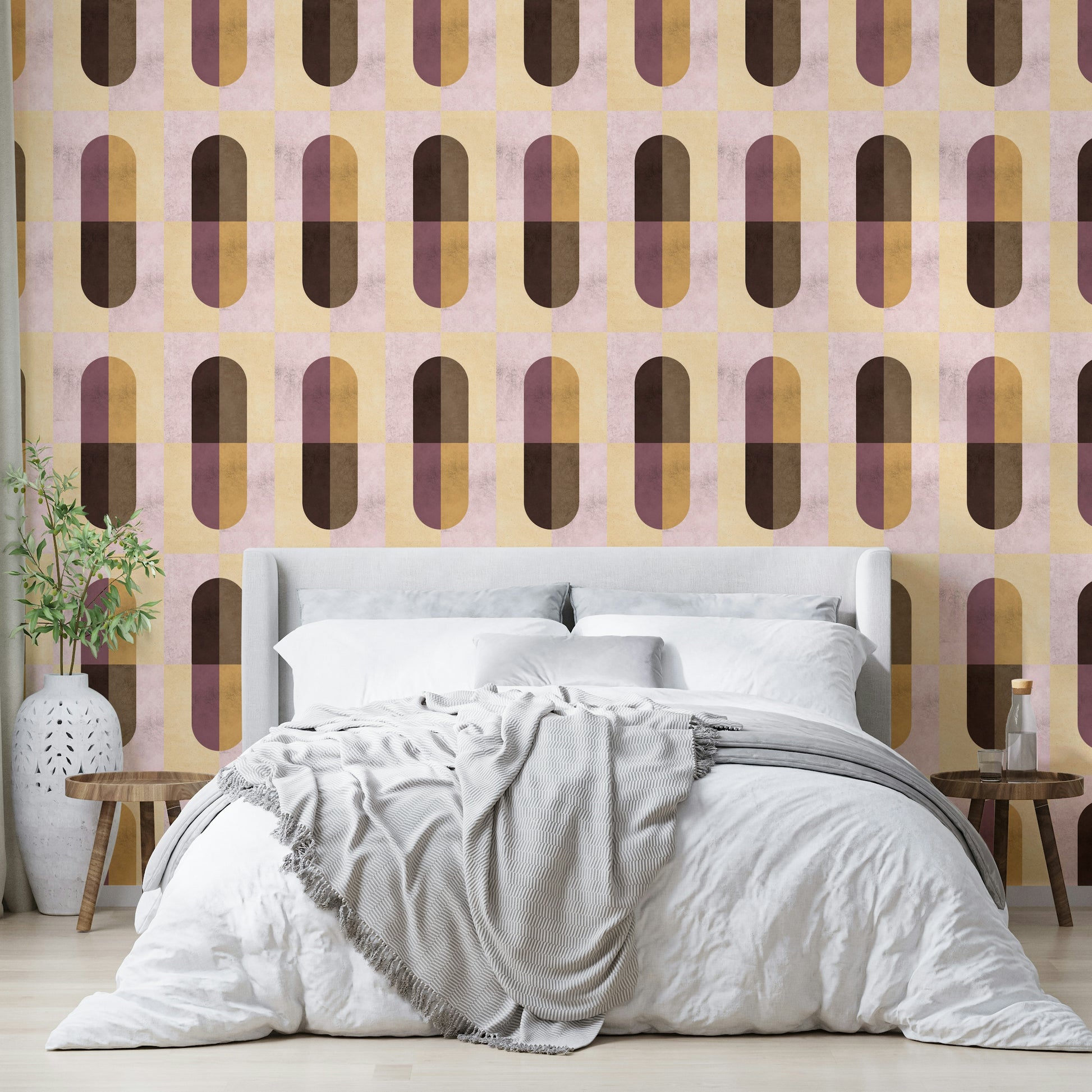 Earthy Geometric wallpaper behind a white upholstered bed with a grey throw and an olive branch vase