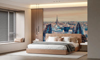Eiffel Tower View wallpaper mural with the Paris skyline at dusk above a tan upholstered bed in a warm bedroom