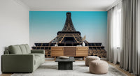 Eiffel's Azure Ascent wallpaper mural with the Eiffel Tower behind a sage green sofa and wood sideboard in a living room