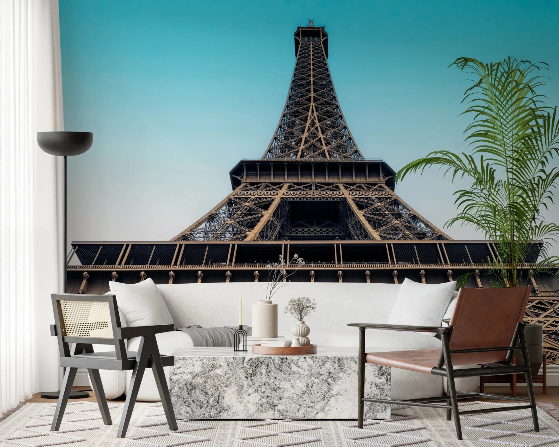 Eiffel's Azure Ascent wallpaper mural of the Eiffel Tower above a white sofa and marble table in a living room