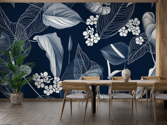 Dark Blue Anthurium & Blue Leaves wallpaper with white line-art flowers behind a wooden dining table and potted palm