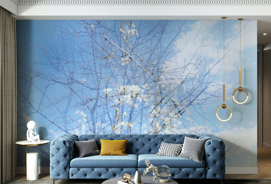 Ethereal Floral Sky Art serene dreamy blossoms wall mural behind a blue tufted velvet sofa with gold ring pendants in a living room
