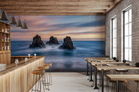 Blue coastal wall mural with sunset sky, ocean mist, and sea stacks
