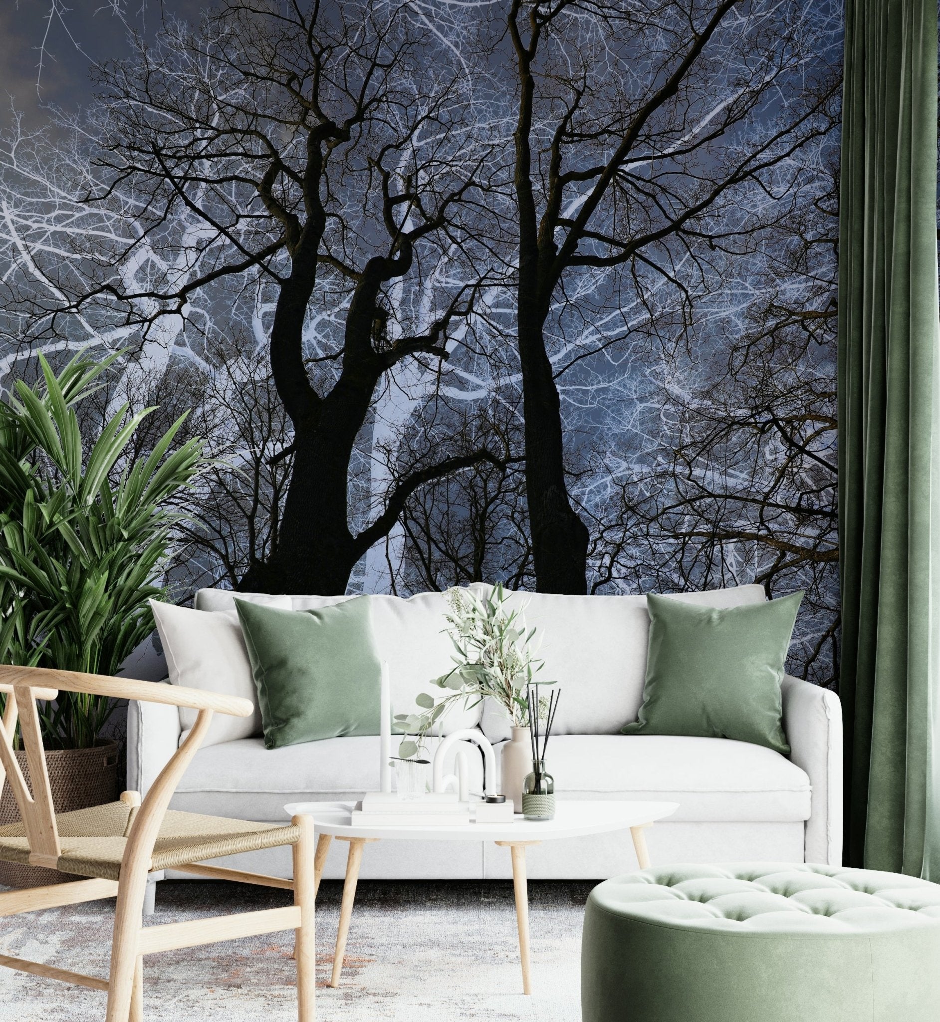 Ethereal Tree Silhouette wall mural of dark trees against a blue sky behind a white sofa with sage green pillows