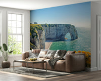 Close view of yellow blooms on cliffside wall mural, green color leaves with ocean wallpaper horizon