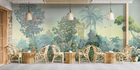 Exotic Paradise wallpaper mural of palms, flowers and peacocks in green tones behind rattan chairs and tables in a cafe setting