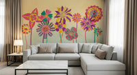 Whimsical Fantasy Flowers wallpaper mural of bright flowers behind a grey sectional sofa and marble table in a living room