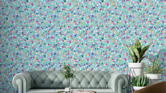 Confetti Festive Colorful Dots wallpaper in turquoise behind a mint green tufted Chesterfield sofa and plants