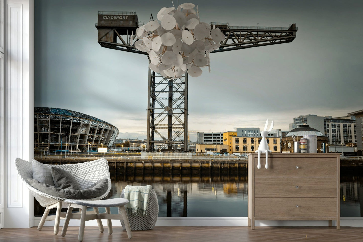 Finnieston Crane wall mural of the Clydeport crane behind woven chairs, a wood dresser and disc chandelier