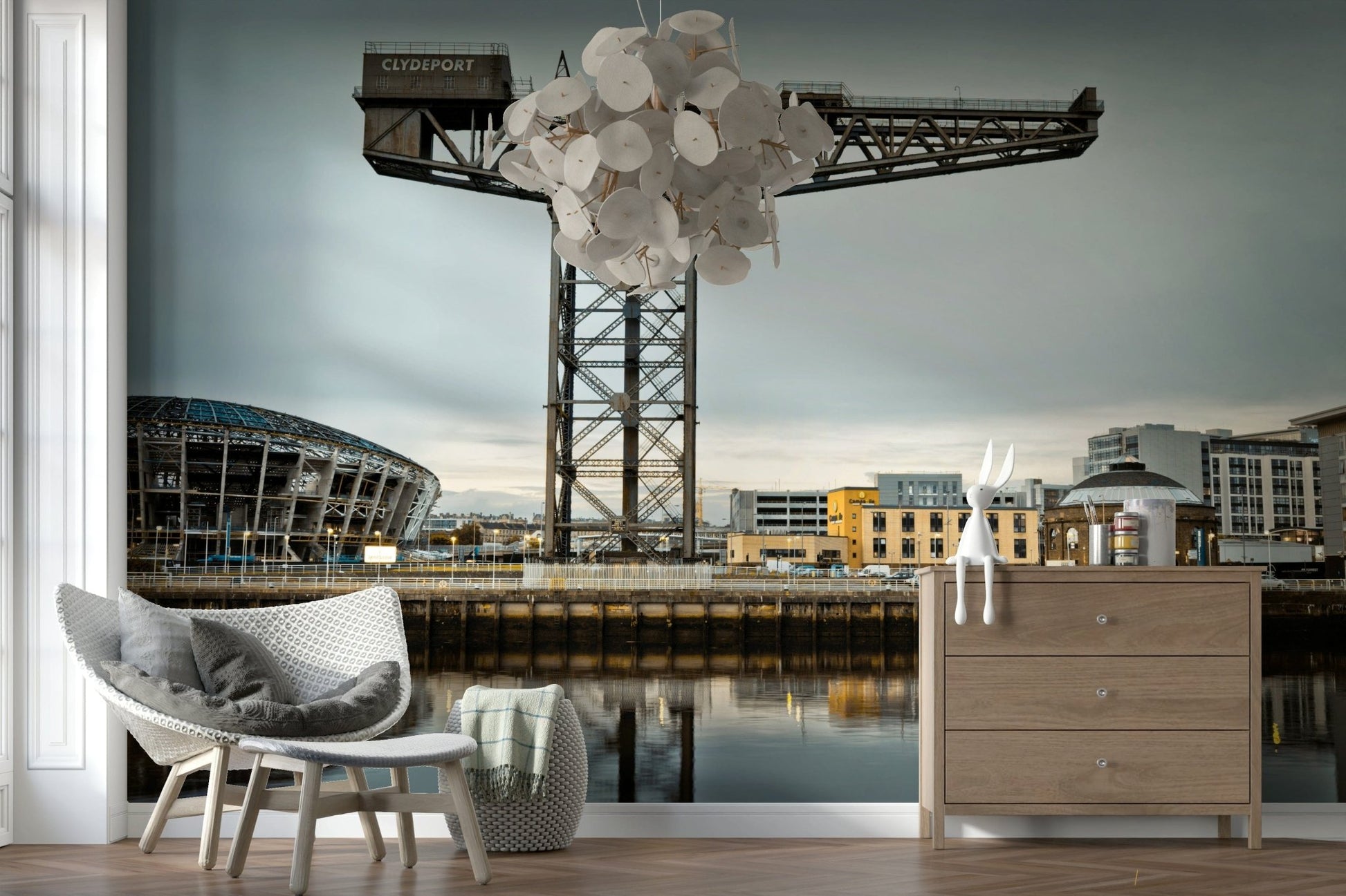 Finnieston Crane wall mural of the Clydeport crane behind woven chairs, a wood dresser and disc chandelier