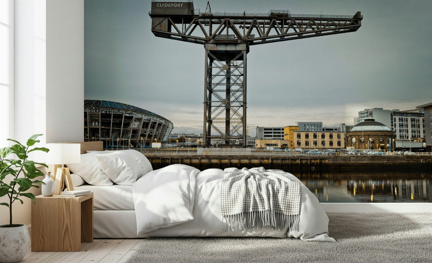 Finnieston Crane wall mural of the Glasgow quay above a white bed with a wood nightstand and fiddle-leaf plant