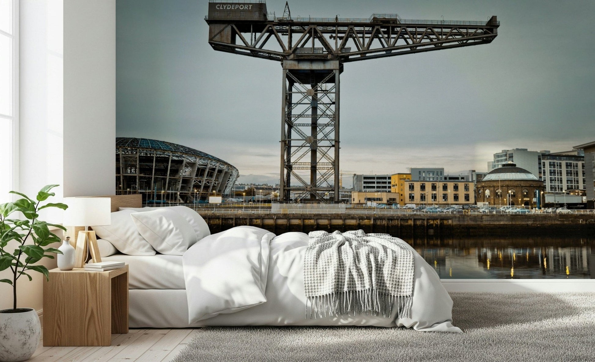 Finnieston Crane wall mural of the Glasgow quay above a white bed with a wood nightstand and fiddle-leaf plant