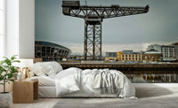 Finnieston Crane wall mural of the Glasgow quay above a white bed with a wood nightstand and fiddle-leaf plant
