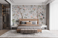 Chinoeserie Floral design wallpaper mural with flowering trees and birds behind a tan upholstered bed in a bedroom