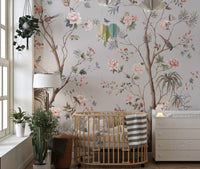 Chinoeserie Floral design wallpaper mural in gray with pink blooms and birds behind a wooden crib in a nursery