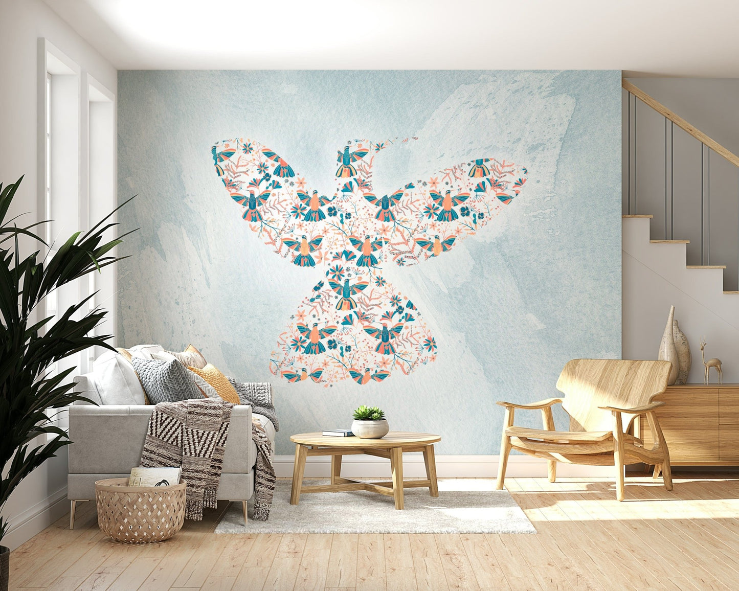 Floral Hummingbird wall mural in coral and teal on blue behind a grey sofa in a living room