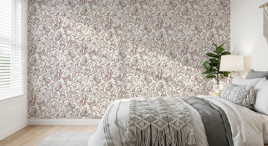 Floral Line Dance wallpaper in burgundy roses behind a grey bed with macrame throw and a leafy plant
