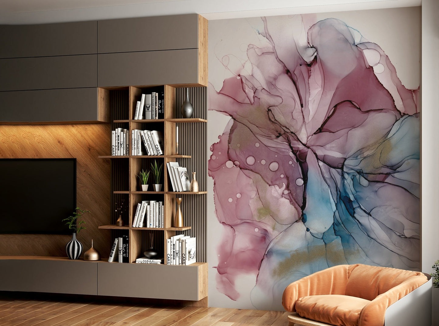 Fluid Dreamscape wallpaper mural of pink, blue and gold ink art beside a wood bookshelf and tan armchair in a living room