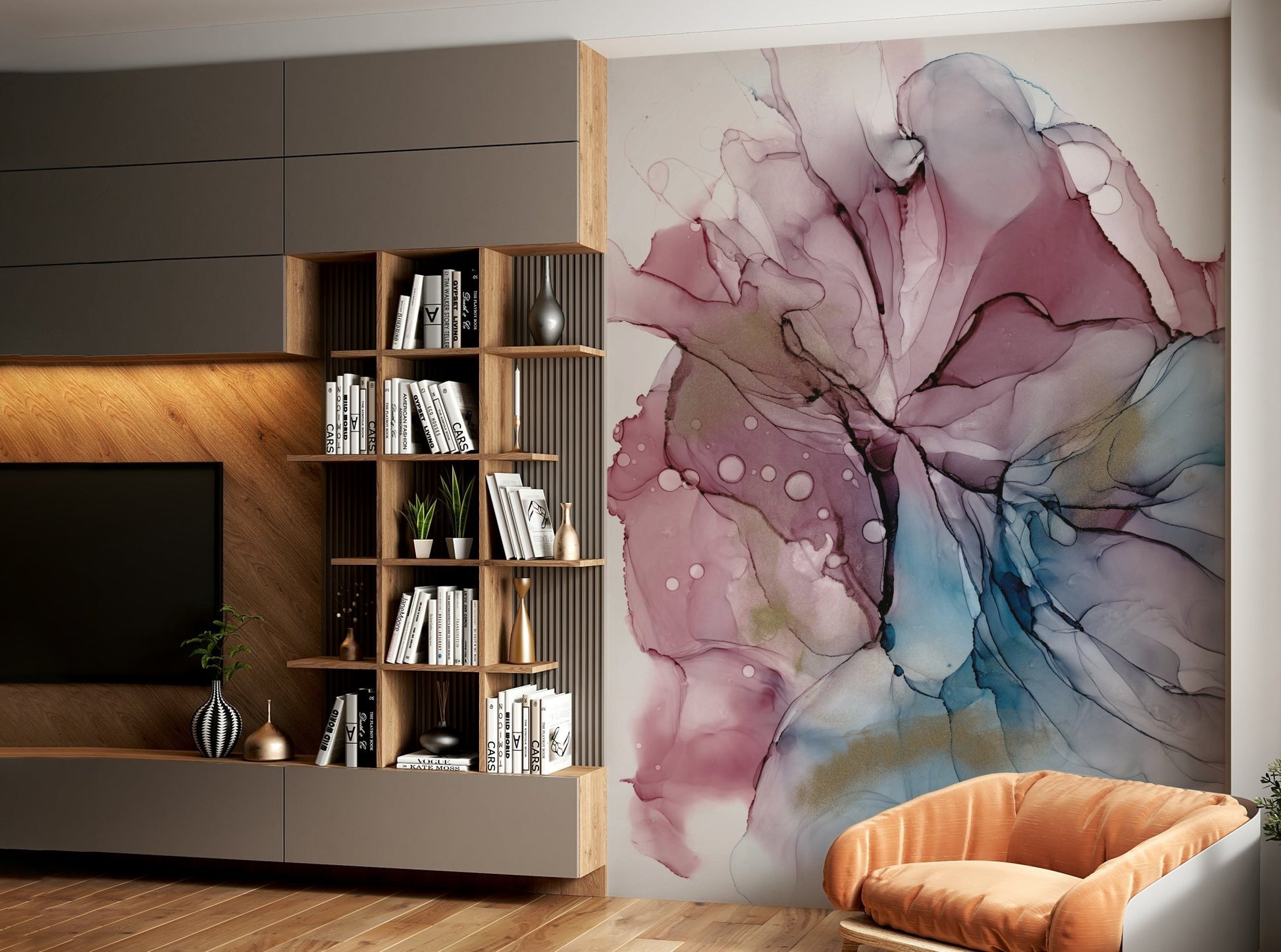 Fluid Dreamscape wallpaper mural of pink, blue and gold ink art beside a wood bookshelf and tan armchair in a living room