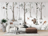 Forest Haven wallpaper mural of a watercolour birch forest with bear and deer behind a white sofa and leather ottoman in a living room