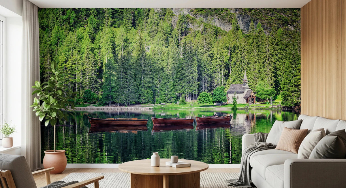 Forest Lake Retreat wallpaper mural with green pine forest, wooden boats and a chapel behind a cream sofa in a living room