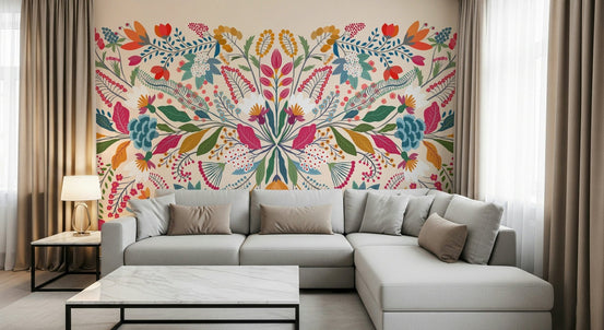 Frida's Garden wallpaper mural of symmetrical folk flowers behind a grey sectional sofa in a living room