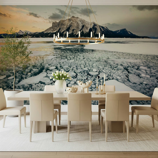 Frozen Bubbles: Mountain Vista wallpaper mural of icy bubble-filled lake and a rocky peak behind a cream dining table and gold chandelier